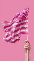 Bold pink American flag displayed by hand against a vibrant pink background in artistic representation of patriotism and creativity photo