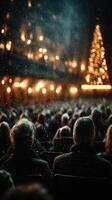 Audience watches a holiday performance in a theater filled with lights and a decorated tree in the background during winter evening photo