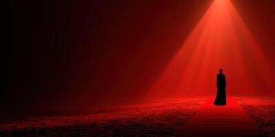 Mysterious figure stands on a red carpet illuminated by a spotlight in a dim, atmospheric setting photo