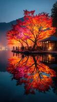 Vibrant autumn foliage reflects on a calm lake at dusk, drawing crowds near an inviting lakeside structure photo