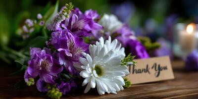 Beautiful floral arrangement featuring purple and white flowers with a thank you note on a wooden surface photo