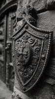 Ornate black shield with intricate design mounted on a stone wall in historic architecture photo