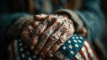 Hands of a veteran resting on an American flag with visible age lines and tattoos during a reflective moment photo