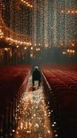 Elderly person seated alone in an empty theater adorned with sparkling lights during a quiet evening photo