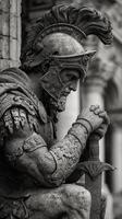 Bronze statue of a warrior in armor resting with sword in historical city square during the day photo