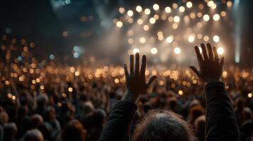 Crowd enjoys live concert with raised hands and glowing lights in the background during an evening performance photo