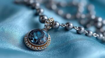 Elegant blue gemstone pendant on a delicate chain resting on shimmering fabric photo
