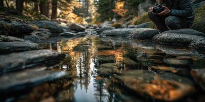 Photographer capturing reflections while sitting by a serene river in autumn photo