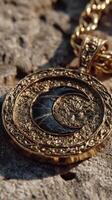 Intricate gold pendant featuring a crescent moon design, resting on textured stone surface under natural light photo