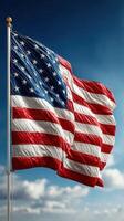 American flag waving under a clear blue sky with soft clouds during the day photo