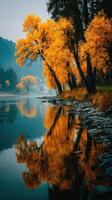 Vibrant autumn foliage reflecting in calm river water surrounded by mountains in a serene natural setting at sunset photo