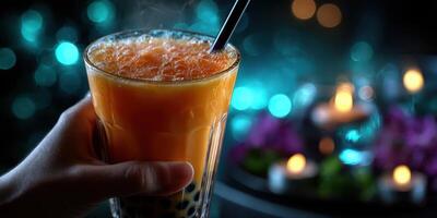 Sipping a refreshing bubble tea drink in a vibrant setting with glowing lights at an evening gathering photo