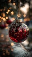 Ornate red Christmas ornament hanging on a tree branch with warm lights in the background during the festive season photo