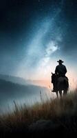 Silhouetted cowboy on horseback under a starry night sky at dawn in a tranquil landscape photo