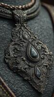 Intricate handmade silver pendant featuring black gemstones set against textured leather background photo