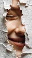 Smiling woman peeking through torn paper in a creative and playful expression photo