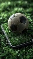 Wet soccer ball rests on artificial grass next to a smartphone during a rainy day photo