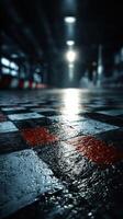 Reflections on a wet checkered floor in an industrial space during nighttime photo