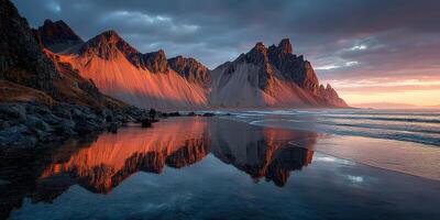 Stunning sunset over Vestrahorn mountain reflecting in calm waters on a serene beach in Iceland photo