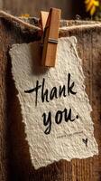 Thank you note hanging on rustic wood with clothespin in warm natural light photo