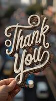 Creative handmade thank you sign held against a blurred urban backdrop with light traffic during the day photo