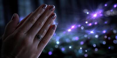 Hands in a prayer position with shimmering lights in the background during a spiritual moment at dusk photo