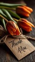 Bouquet of orange tulips with a thank you tag captured in warm natural light photo