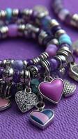 Colorful beaded bracelets with heart charms displayed on a vibrant purple background in midday light photo