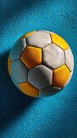 Colorful soccer ball resting on a blue wall in bright light, showcasing details and textures of the ball's surface photo