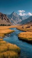 Majestic mountains and serene river flow through golden grasslands under a clear blue sky in the highlands photo