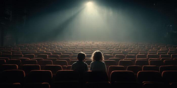 Two children sitting in an empty theater, captivated by a spotlight on the stage during a quiet moment photo