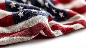 Old and faded American flag textile draped gracefully on a white surface showcasing its vibrant colors and star pattern photo