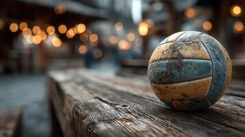 Old volleyball rests on a rustic wooden table in a warm outdoor setting with bokeh lights during the evening hours photo