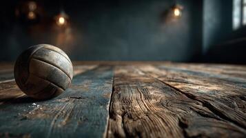 Vintage volleyball resting on an aged wooden floor in a dimly lit indoor gymnasium during late afternoon photo