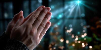 Hands are clasped together in a peaceful gesture, illuminated by soft light filtering through a dark background photo