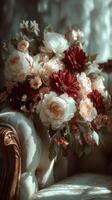 Floral arrangement of light and dark blooms on a vintage sofa in a softly lit setting photo
