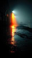 Evening glow from streetlights reflects on wet ground near water during foggy night walk photo