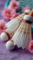 Shuttlecocks arranged with delicate flowers on a purple surface for a vibrant badminton setup photo