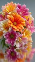 Brightly colored flower bouquet with orange, pink, and white blossoms on a reflective surface photo