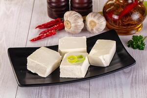 A black plate with four pieces of tofu on it photo
