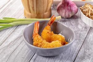 A bowl of fried shrimp sitting on a table photo