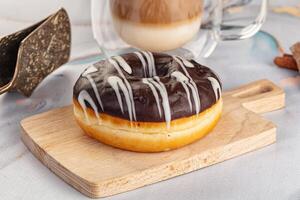 A donut on a cutting board next to a cup of coffee photo