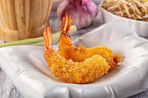 Fried shrimp on a white plate with a bowl of rice photo