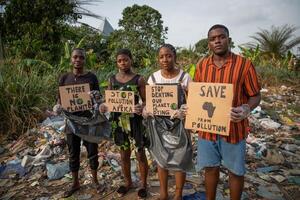 A group of young African activists protest with signs against pollution, they are in front of an illegal landfill and they are about to remove the waste photo