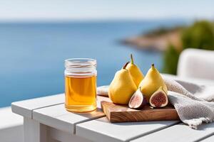 Ripe figs, pears and honey arranged on an outdoor table with a beautiful seashore in the background photo