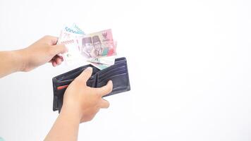 Yogyakarta, Indonesia, 2025 - Hand taking several Indonesian Rupiah banknotes with different values from wallet isolated on white background photo