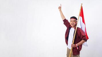Indonesian man holding stick with red and white flag of Indonesia and showing number one sign with finger isolated on white background photo