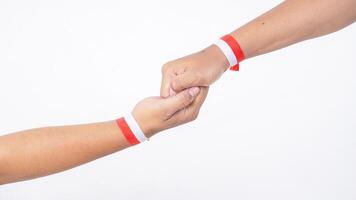 Two men hands with red and white wristband gripping each other isolated on white background photo