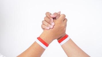 Close up of two men hands with red and white wristband doing unity handshake or clasping isolated on white background photo