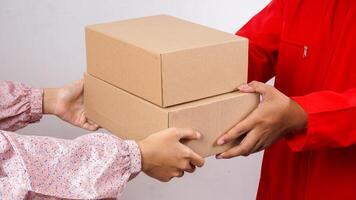 Close up of delivery man in red uniform and a customer holding package boxes parcel together isolated on white background photo